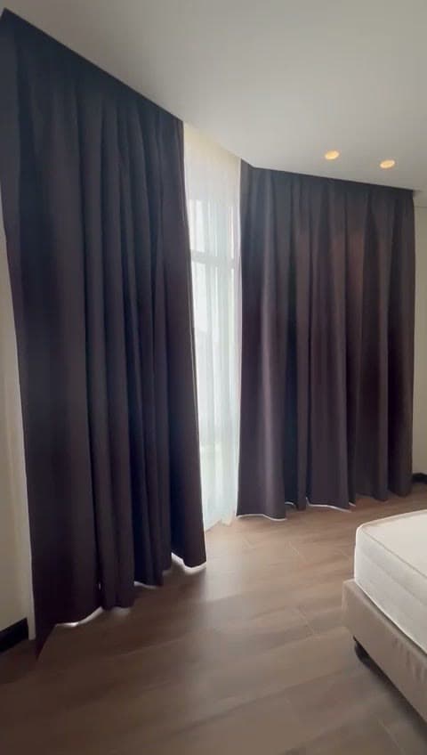 Slaapkamer met dichte donkere verduisteringsgordijnen over een doorschijnend gordijn