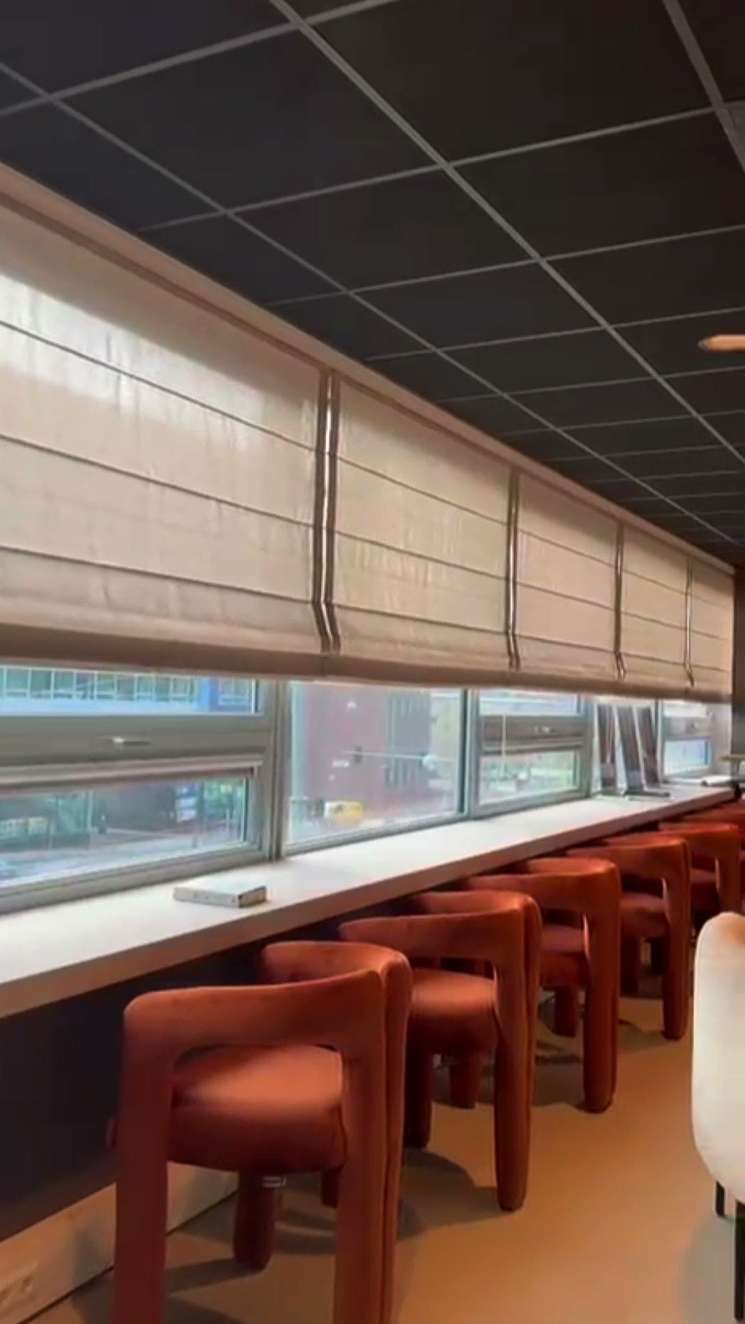Bedrijfsrestaurant met een rij vouwgordijnen boven een lange raamstrook