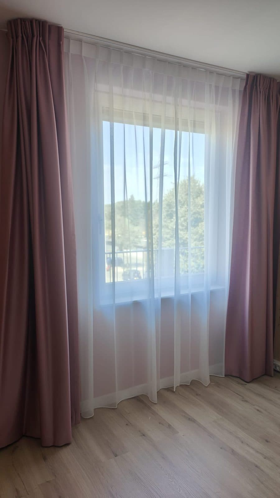 Slaapkamer met oudroze overgordijn en vitrage erachter