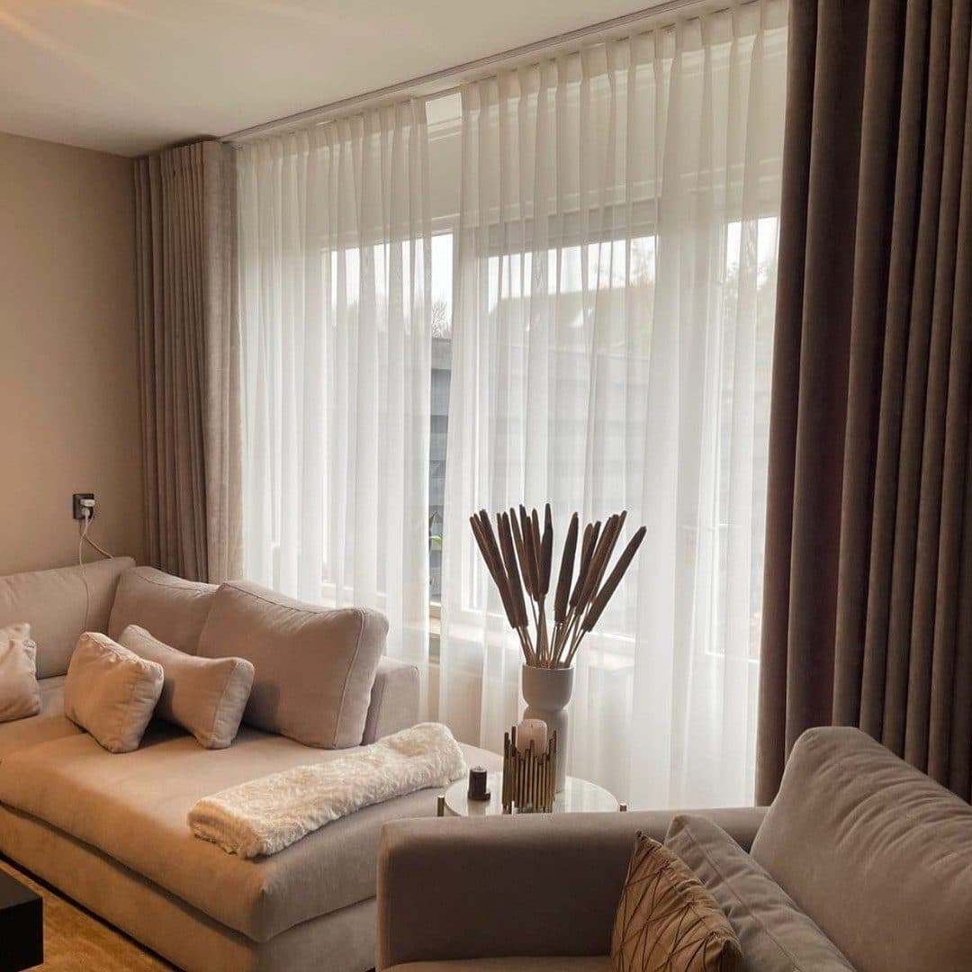 Warme woonkamer met witte vitrage over de hele raamwand